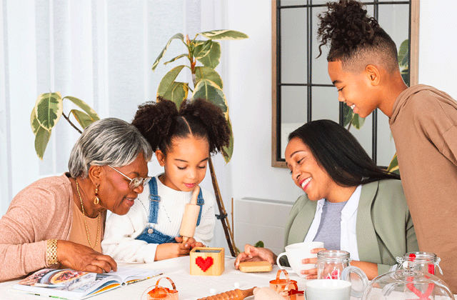 A multi-generational family around a table with a Lovebox showing a pixel-heart message.